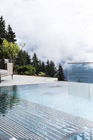A modern outdoor pool area with a lounge chair and a glass-enclosed structure. - Puitalm - Natur I Apart I Hotel (Arzl im Piztal)