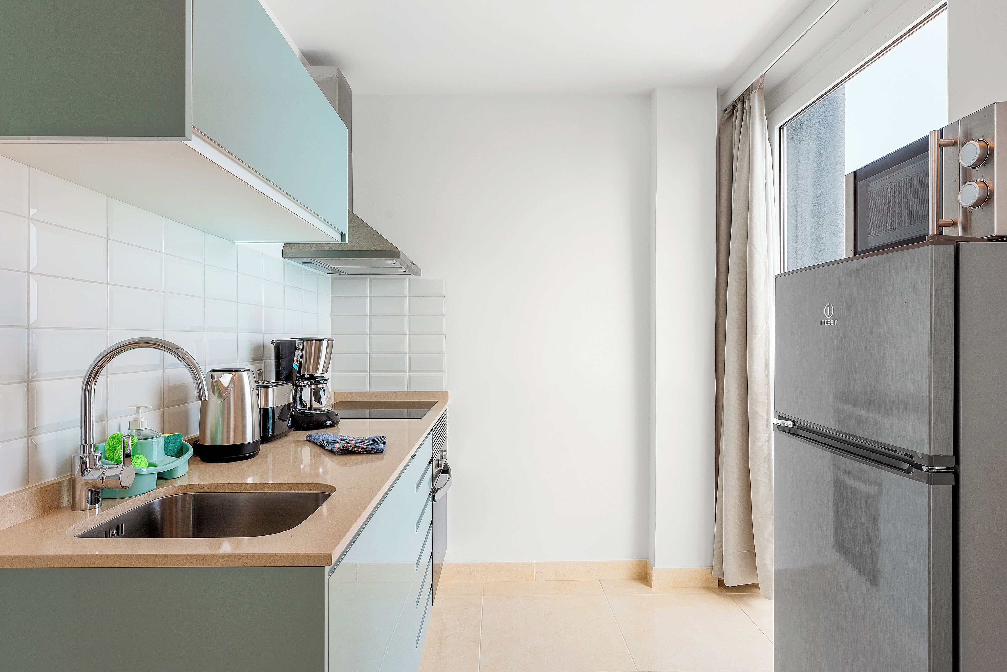 Een moderne keuken met een roestvrijstalen koelkast, een spoelbak en een waterkoker.