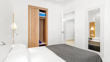 Une chambre d’hôtel moderne avec un grand lit, une armoire en bois, un miroir et une salle de bain avec douche.