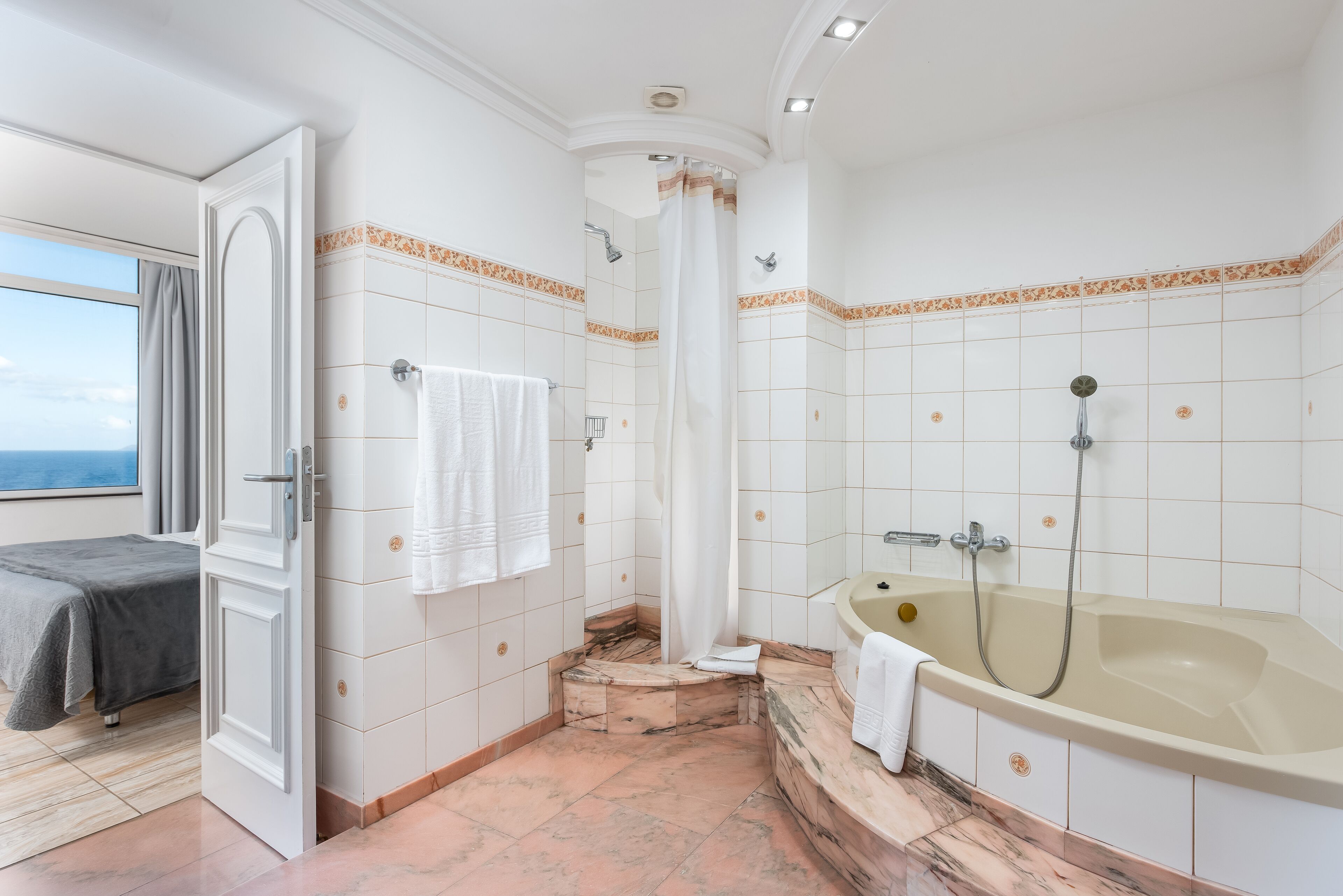 Une salle de bain avec une baignoire, une douche et un lit avec une serviette.