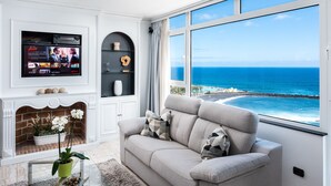 A living room with a large TV, a fireplace, and a view of the ocean. - Ocean Vistas 24 (Puerto de la Cruz)