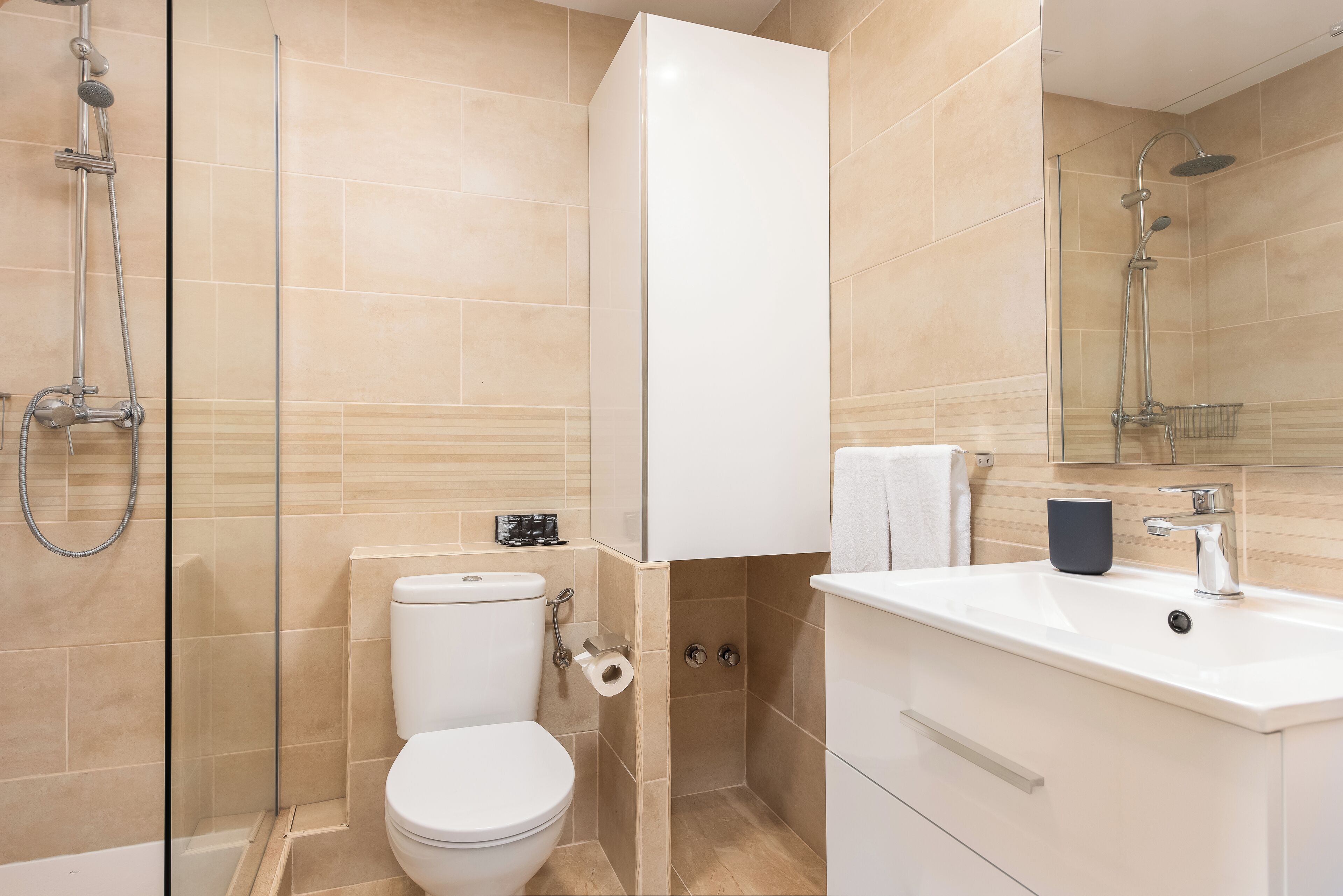 A modern bathroom with a toilet, shower, and sink.