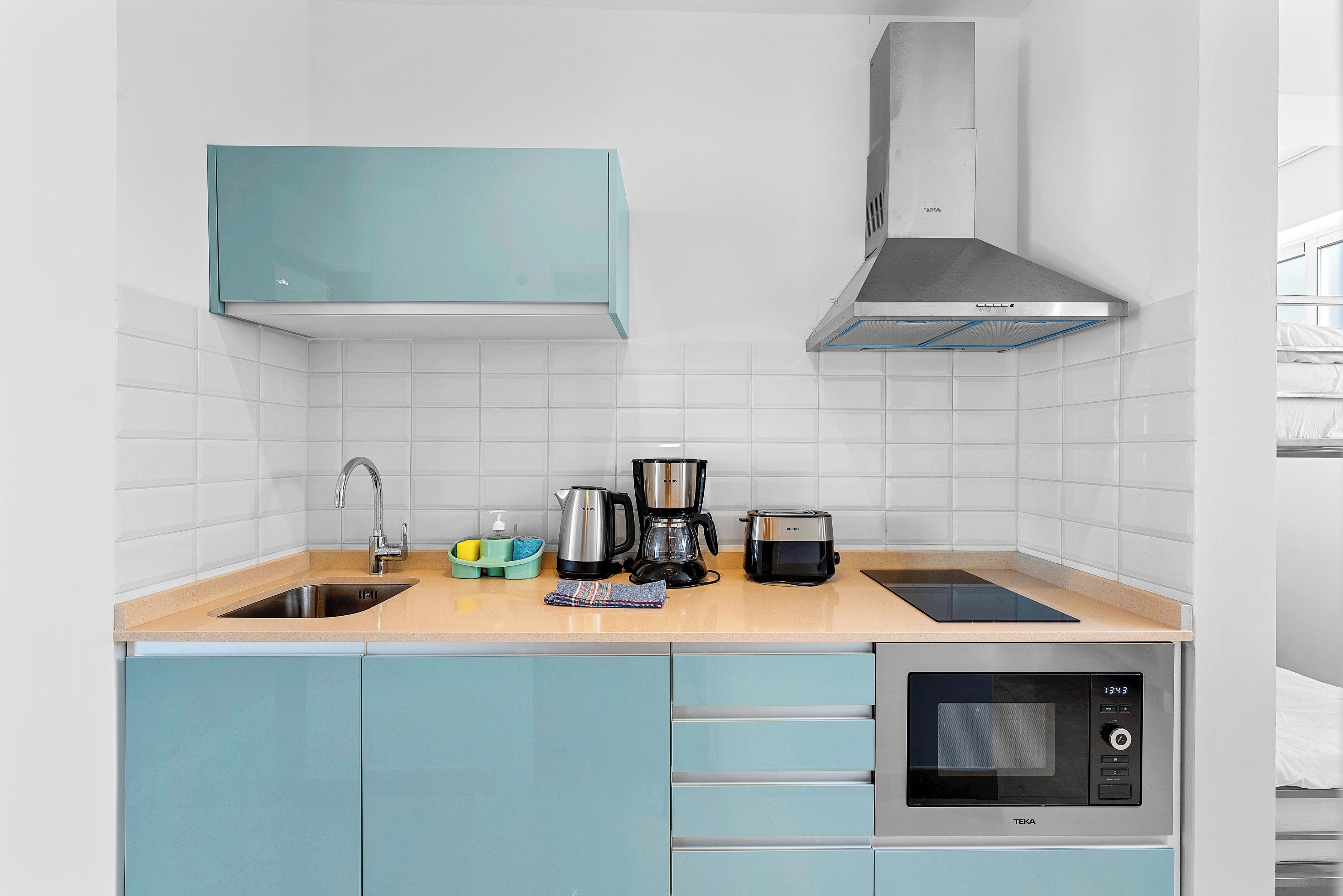 A modern kitchen with a sink, a coffee maker, a toaster, and a microwave.