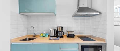 A modern kitchen with a sink, a coffee maker, a toaster, and a microwave.