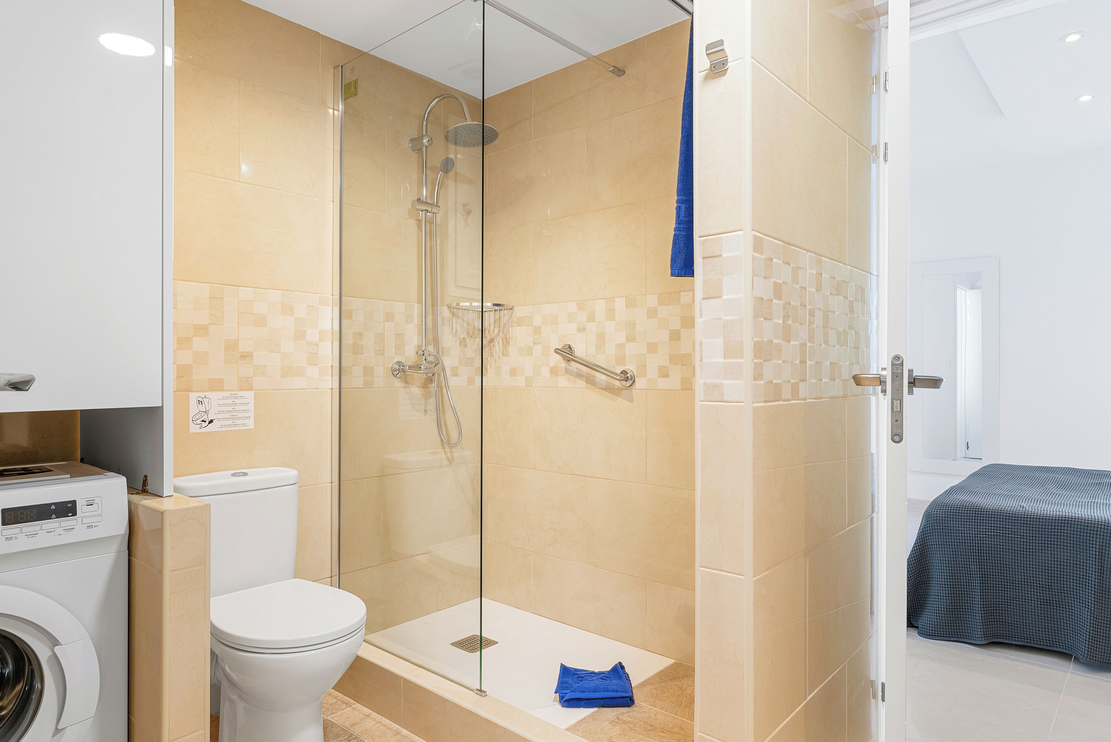 Un baño moderno con ducha de vidrio, inodoro y lavadora.