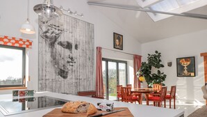 Una cocina moderna con una isla grande, un comedor con sillas rojas y un ventanal amplio.