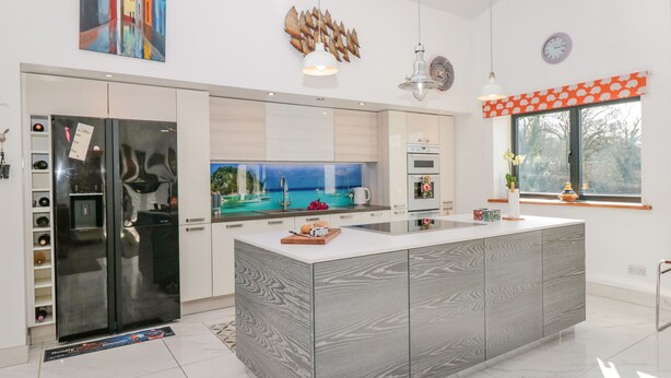 Una cocina moderna con una isla grande, horno empotrado y vistas a la costa.