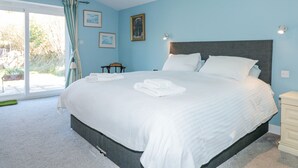 Un dormitorio con una cama grande, una mesita de noche, una silla y una ventana con cortinas.