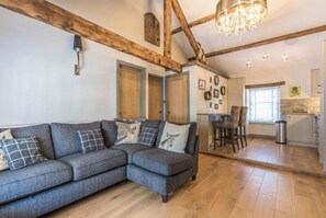 Relax in this inviting living area with a large sofa, exposed beams, and a chandelier.