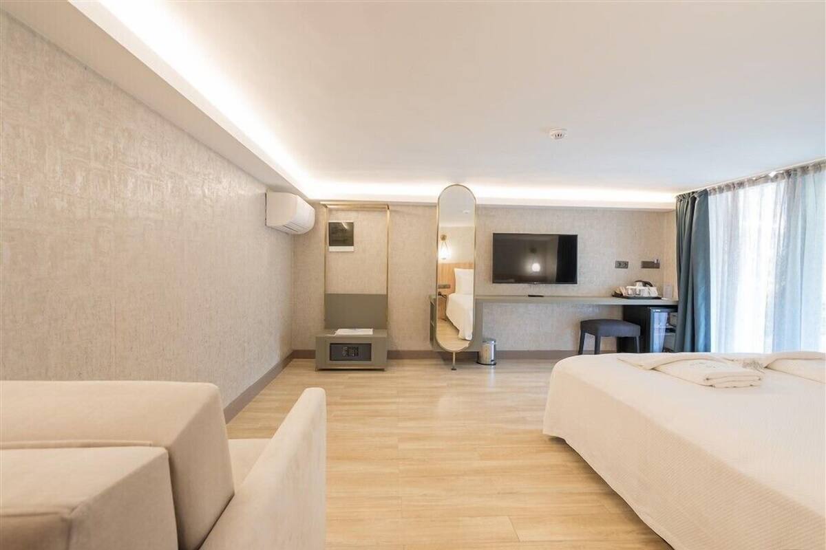 A hotel room with a bed, a desk, a chair, a television, and a mirror.