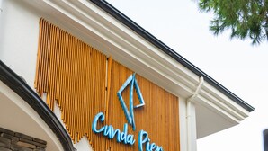 A building with a wooden facade and a sign that reads "Cinda Pier". There are two wooden chairs outside. - Cunda Pier Otel (Ayvalik)