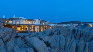 En ejendom ved kysten med en stenfassade, flere værelser og udsigt over det omkringliggende klippelandskab.