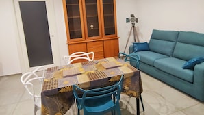 A dining area with a table and chairs, a cabinet, a sofa, and a tripod. - Central apartment in private area (Barletta)