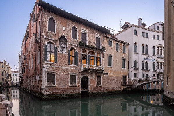A historic building with a canal, a bridge, and a hotel named "Colombina".