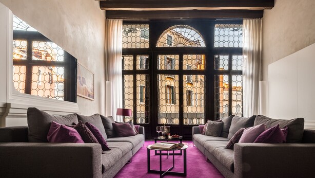 Ein gemütliches Wohnzimmer mit zwei Sofas, einem Couchtisch und großen Fenstern mit Blick auf Gebäude.