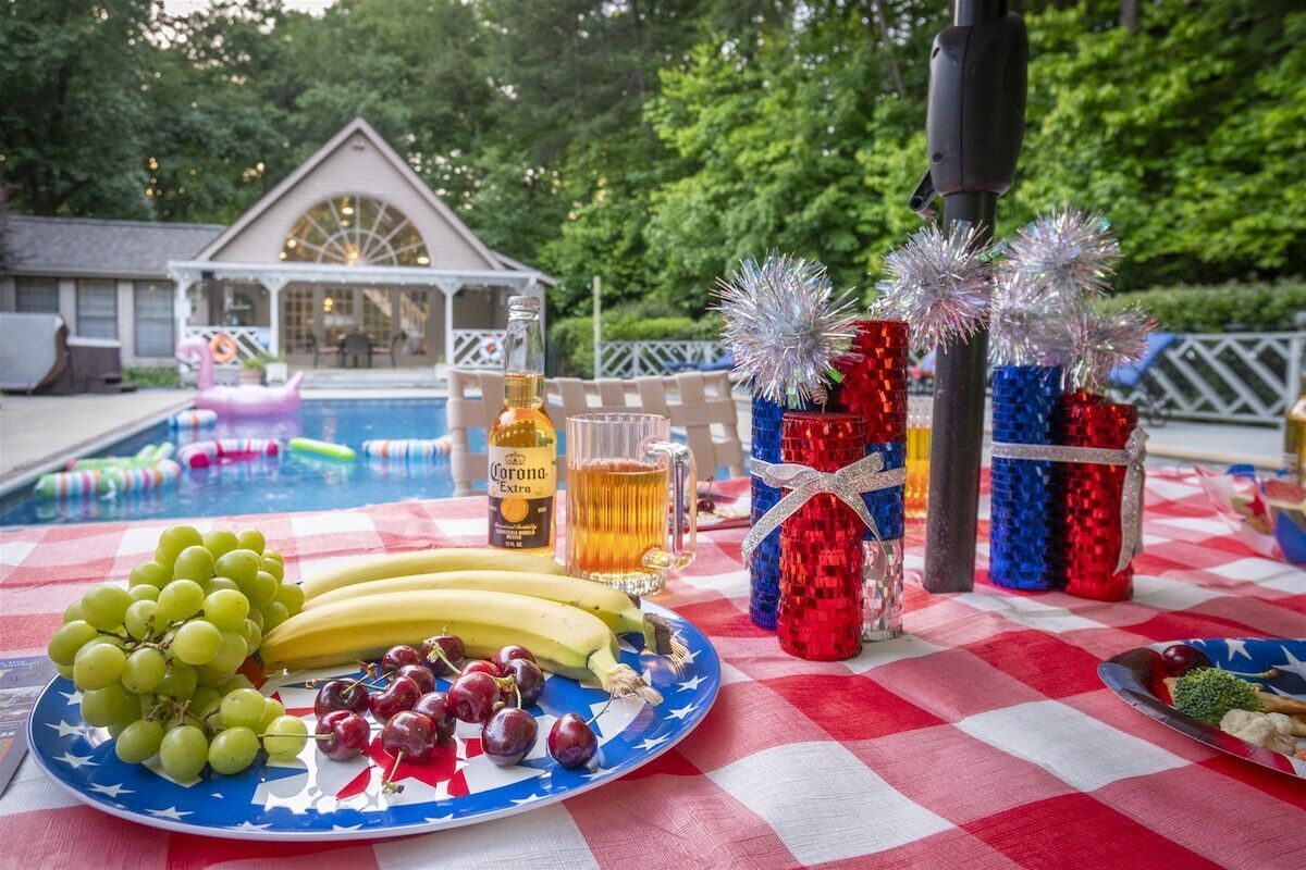A poolside table with a plate of fruit, a Corona Extra bottle, and decorative vases.