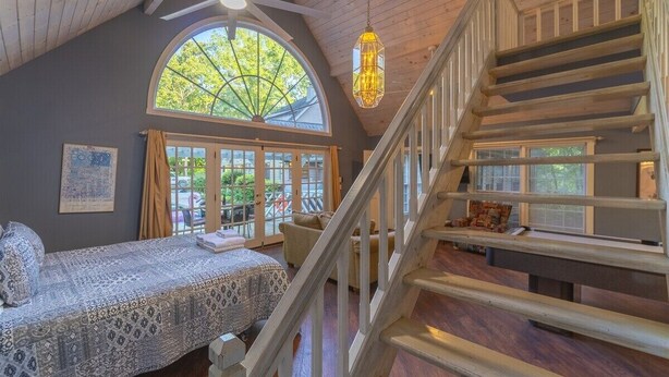A bedroom with a large window, a staircase, and a chandelier. - Spacious 5BR Helen villa with private pool, hot tub, and game room. (Helen)