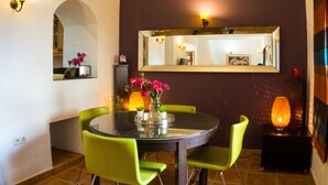 A dining area with a round table, green chairs, a vase of flowers, a mirror on the wall, and a floor lamp. - Townhouse in the heart of Marbella Old Town (Marbella)