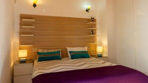 A bedroom with a wooden slatted headboard, two bedside lamps, a purple bedspread, and striped pillows. - Townhouse in the heart of Marbella Old Town (Marbella)