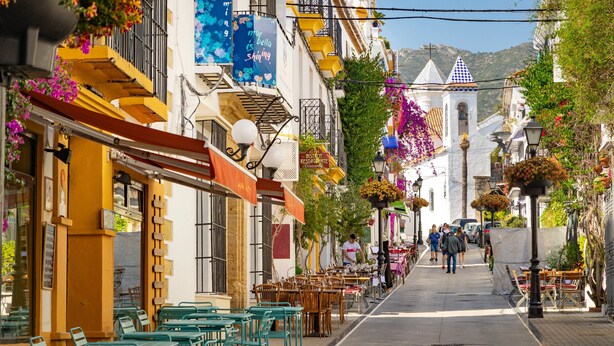 A narrow street lined with cafes and restaurants, featuring outdoor seating and hanging flower baskets. - Townhouse in the heart of Marbella Old Town (Marbella)