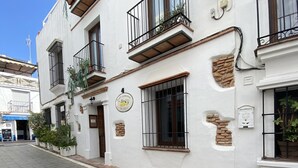 A white building with multiple balconies, a sign indicating a restaurant, and a paved street. - Townhouse in the heart of Marbella Old Town (Marbella)