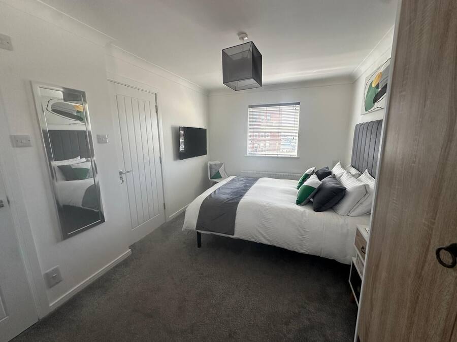 A bedroom with a bed, a TV, a window, and a door.