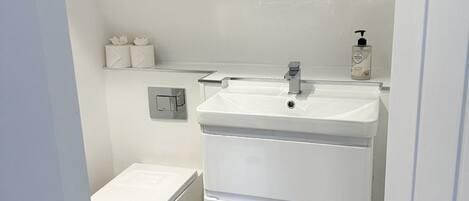 Un baño moderno con lavamanos, inodoro y tocador blancos.