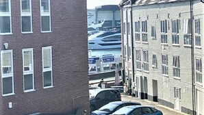 A narrow street with parked cars and a building with multiple windows. - Anchorage (Poole)