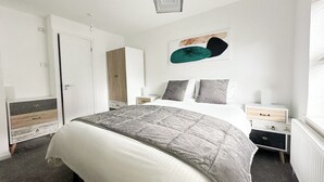 A bedroom with a bed, bedside tables, a wardrobe, and a painting on the wall. - Anchorage (Poole)