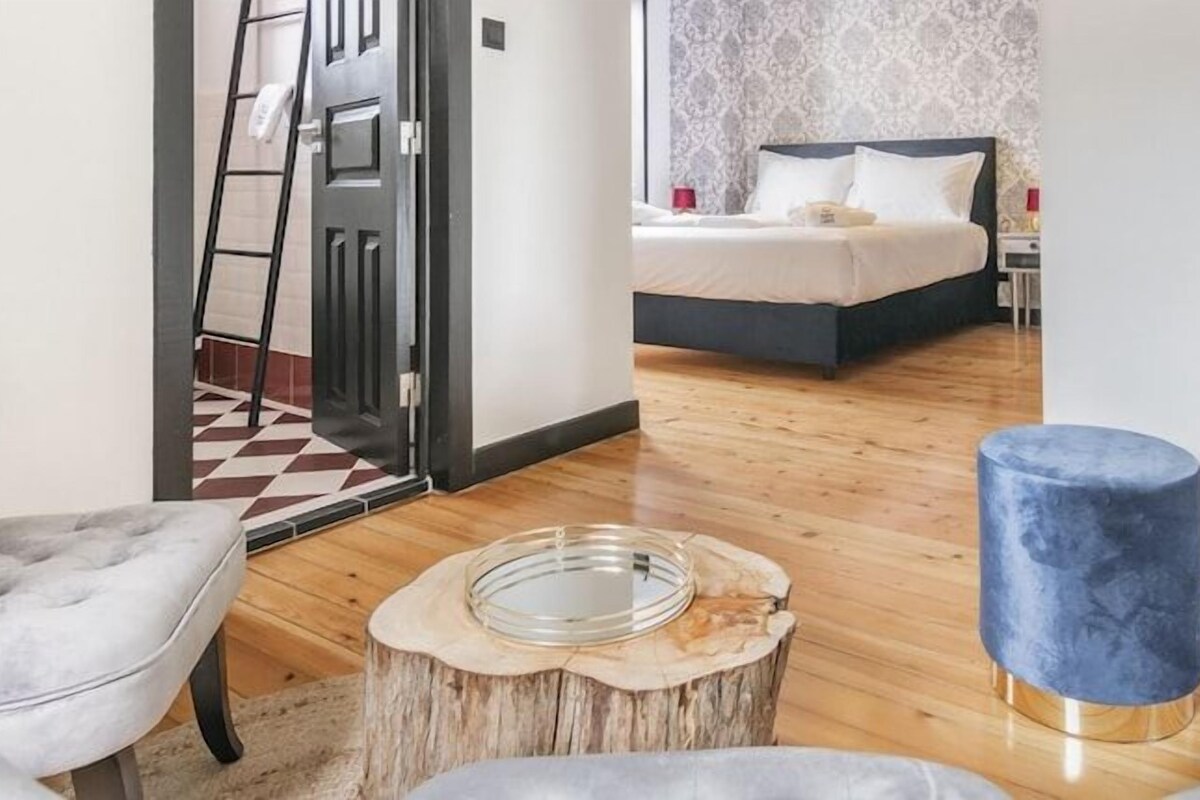 Et moderne hotelværelse med en seng, et siddeområde med et rundt bord og en synlig trappe.