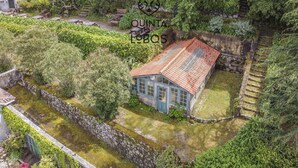A rustic house with a tiled roof, surrounded by lush greenery and a stone wall. - Quinta dos Lobos Boutique Hotel - Nature Experience (Sintra)