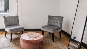 A room with two grey upholstered chairs, a pink ottoman, a floor lamp, and a window with blinds. - Quinta dos Lobos Boutique Hotel - Nature Experience (Sintra)