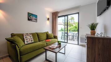 Una sala de estar moderna con un sofá verde, una mesa de centro de madera y un ventanal corredero que da a un espacio exterior.
