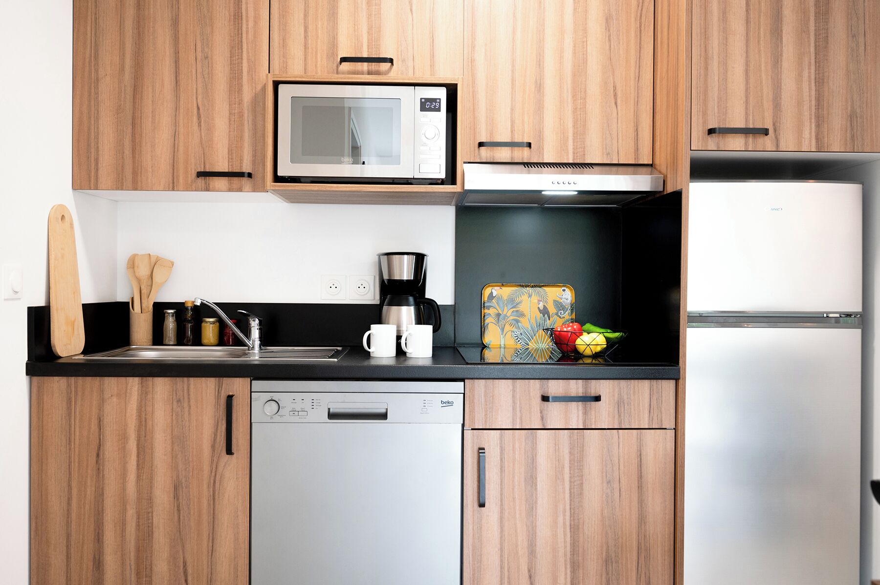 Eine moderne Küche mit Holzausstattung, einer Mikrowelle, einer Kaffeemaschine und einem Geschirrspüler.