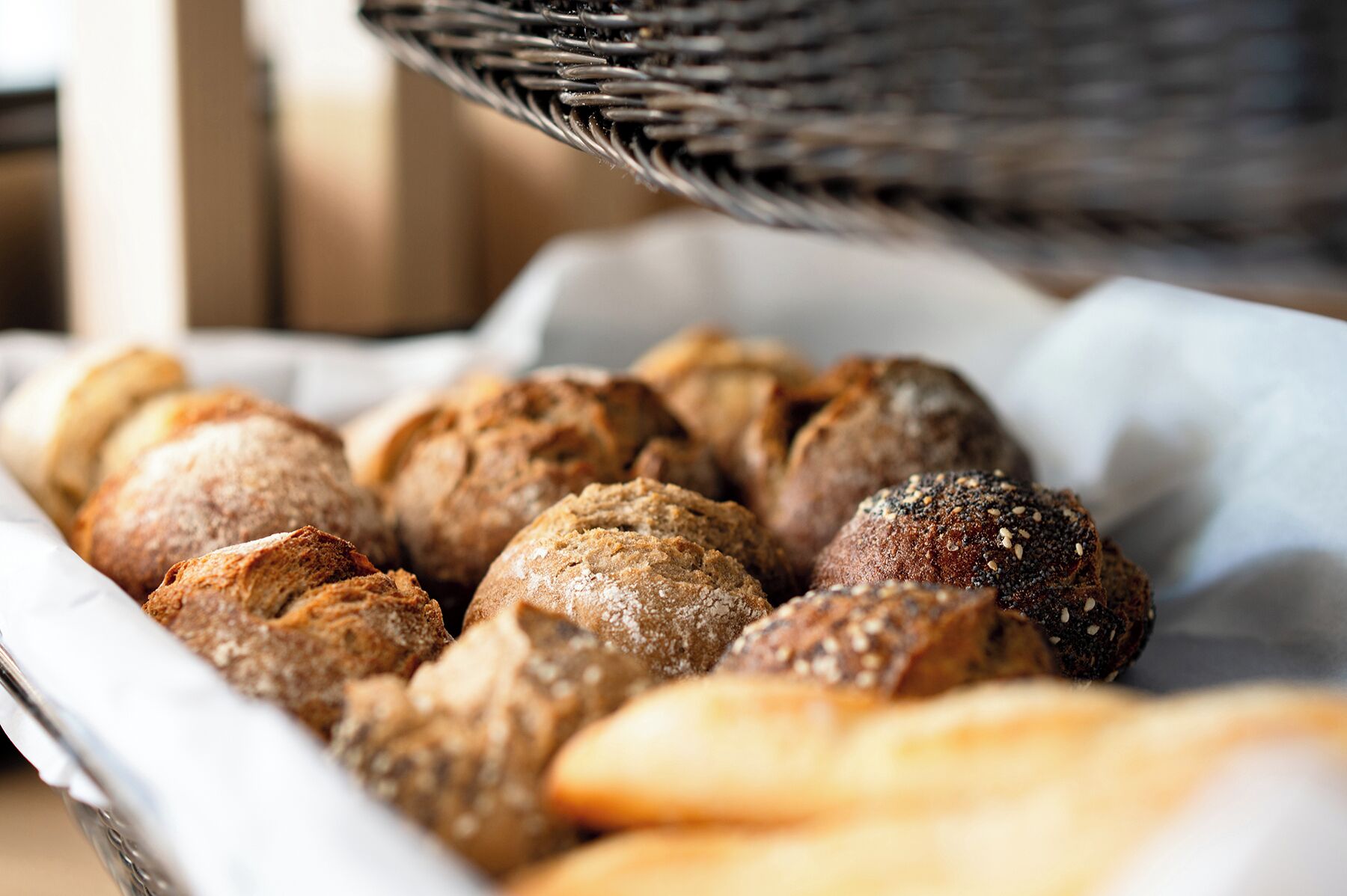 Une assiette contenant un assortiment de petits pains, certains parsemés de graines de sésame et d’autres de graines de pavot.
