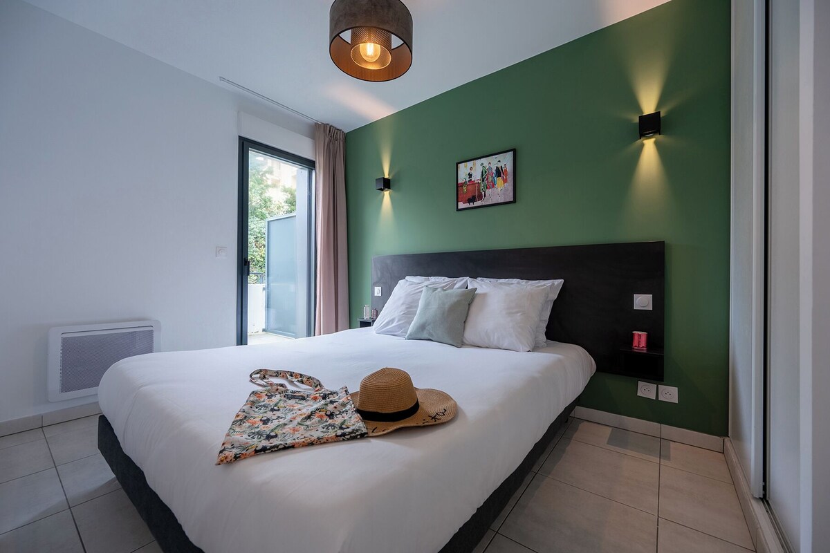 Un dormitorio moderno con una cama grande, una pared de acento verde y una ventana con vistas.