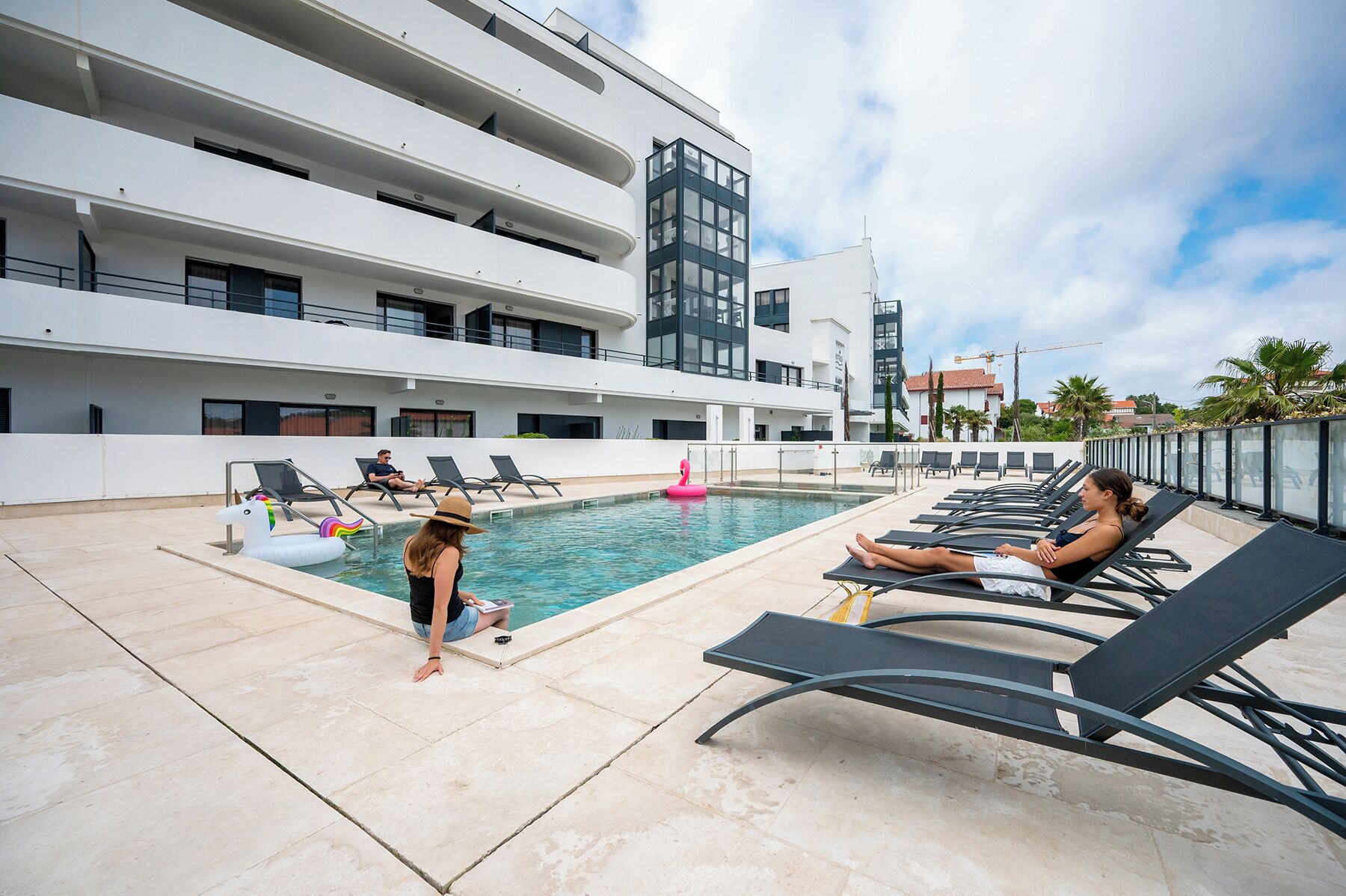 Un área de piscina en la azotea con sillas de descanso y una piscina.