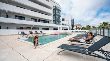 Un área de piscina en la azotea con sillas de descanso y una piscina.