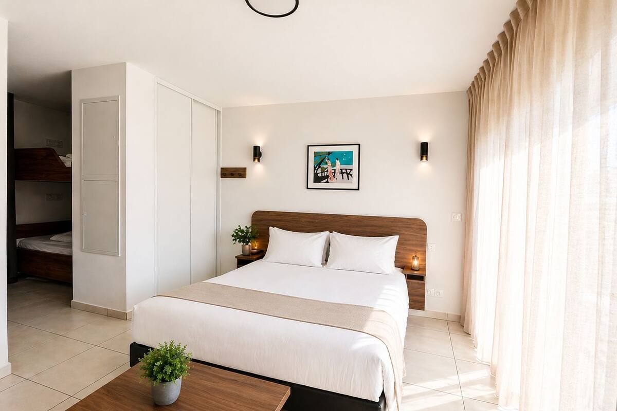 Hotelkamer met een bed, nachtkastjes, een potplant, een aan de muur hangend schilderij en een raam met gordijnen.
