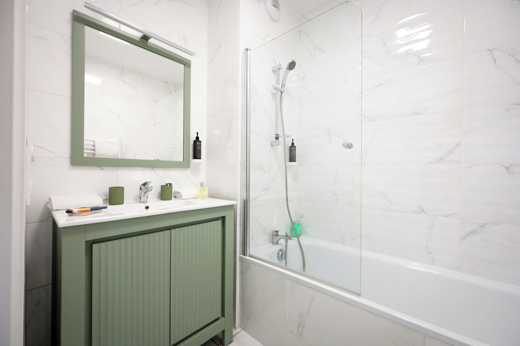 Un baño con tocador verde, un espejo y una ducha con puerta de vidrio.