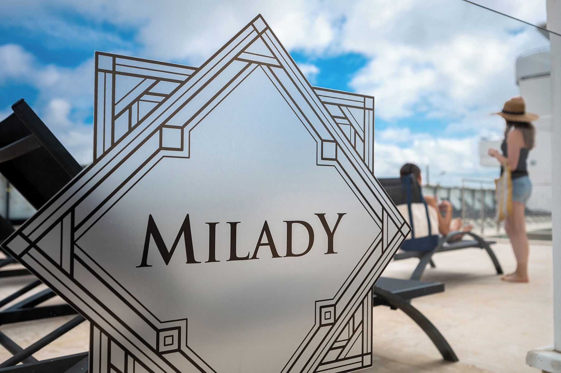 Een bord met de naam 'MILADY' in een geometrisch ontwerp, dat de naam van de locatie aangeeft.