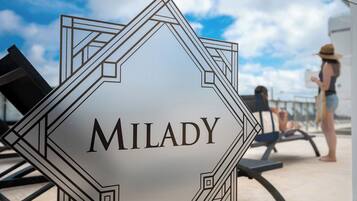 Een bord met de naam 'MILADY' in een geometrisch ontwerp, dat de naam van de locatie aangeeft.