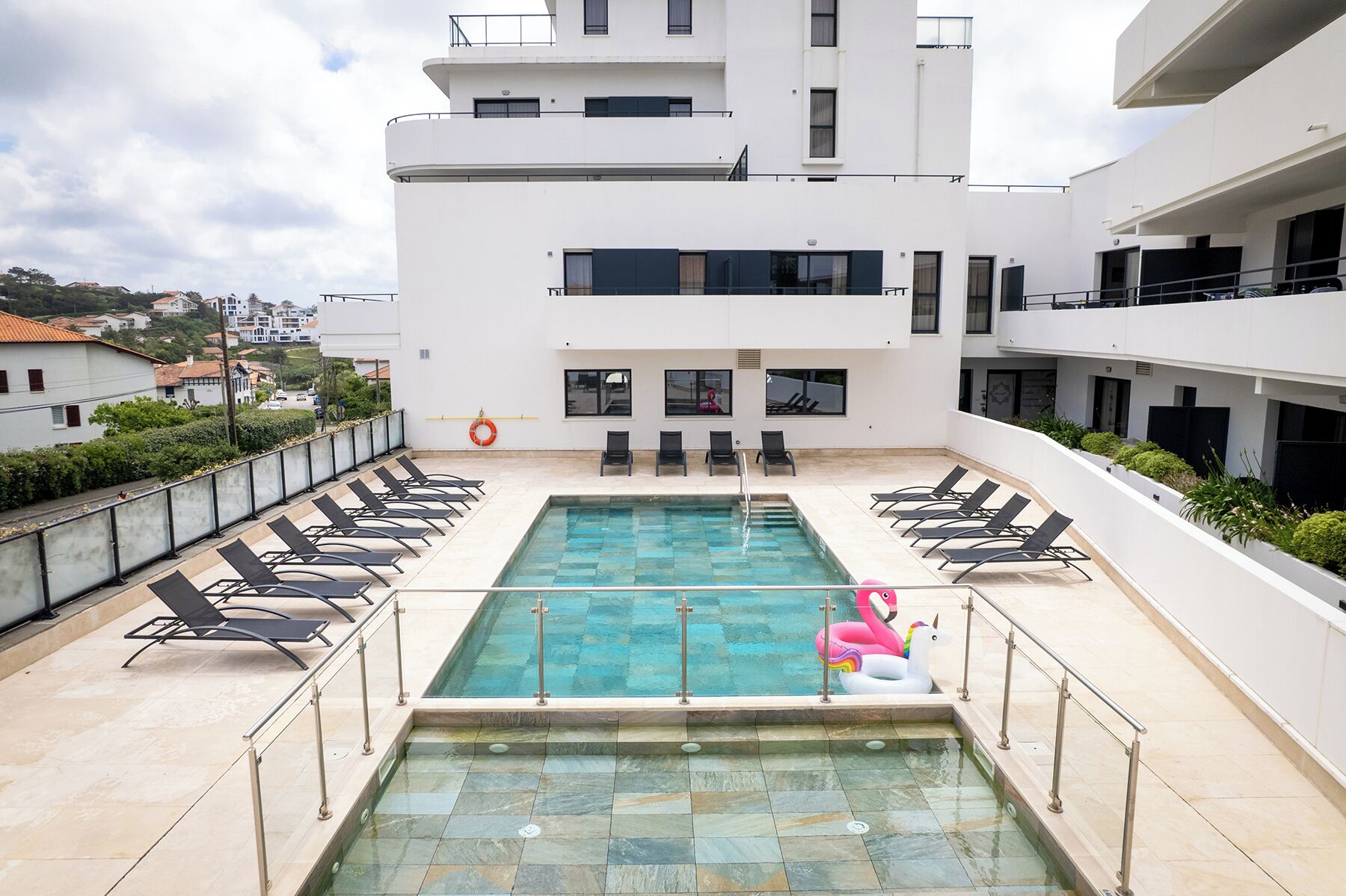 Una piscina en la azotea con sillones de descanso y un flotador.