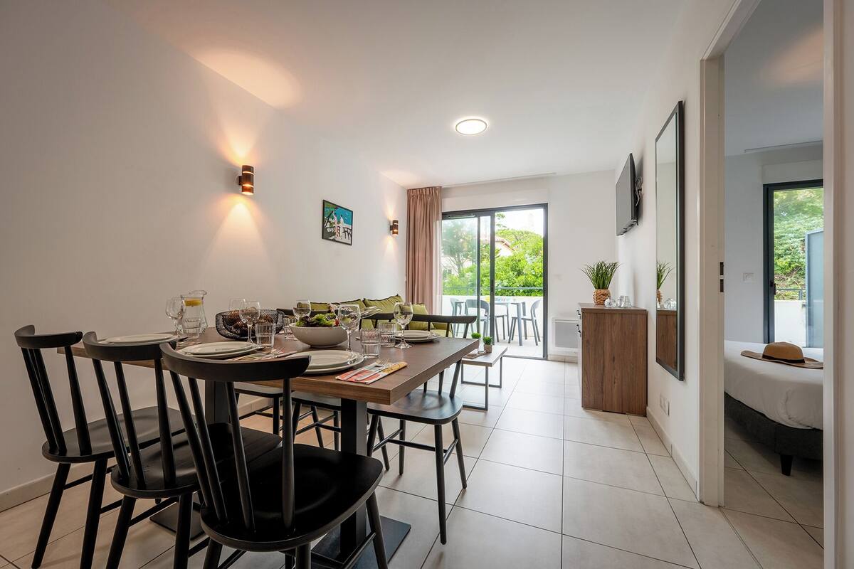 Een moderne eetruimte met een tafel voor vier personen, een bank en een balkon met buitenmeubels.