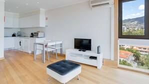 A modern apartment with a kitchen, dining area, and a large window with a city view. - Funchal View Apartment (Funchal)