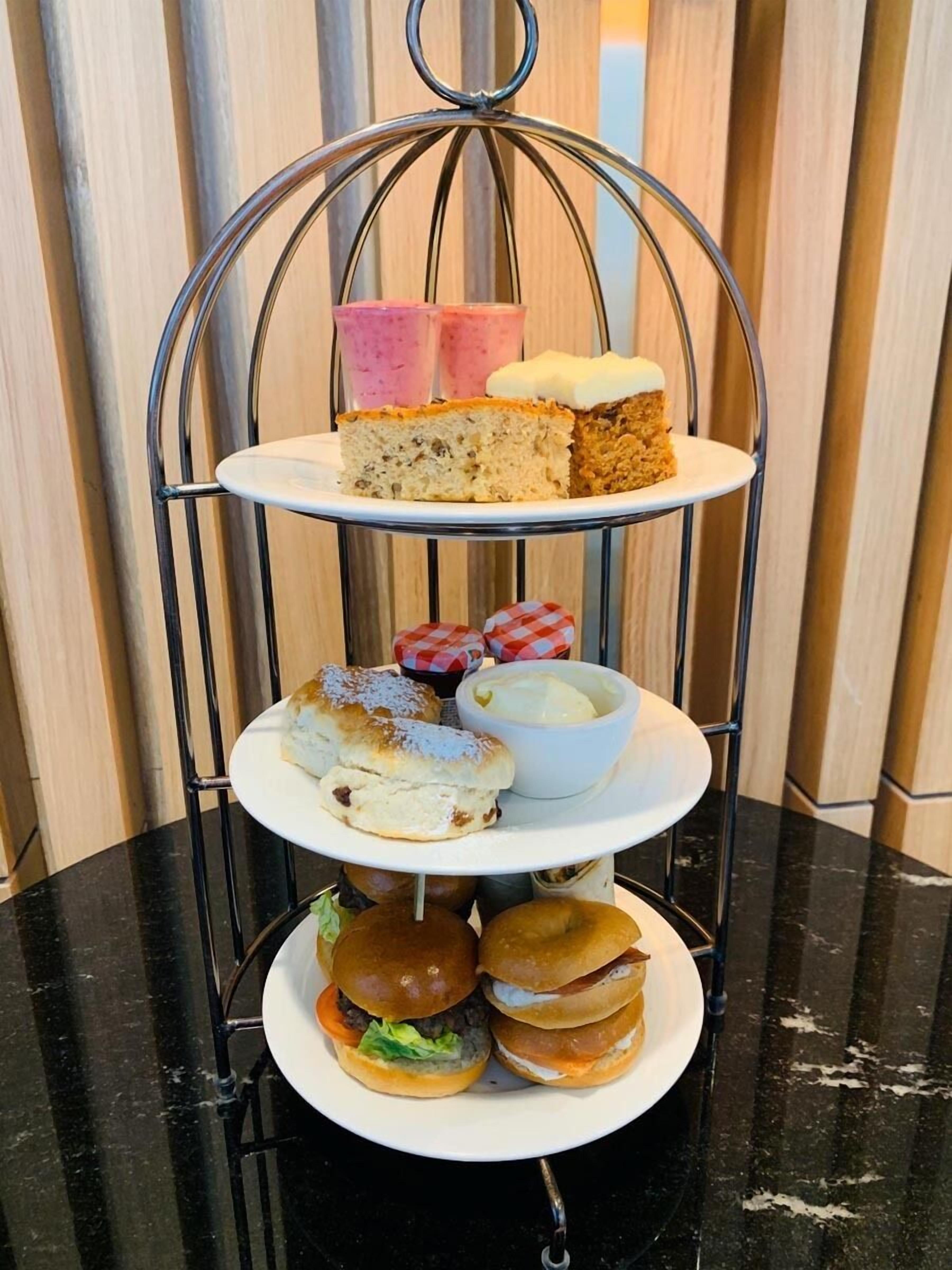 A three-tiered metal stand with various food items.