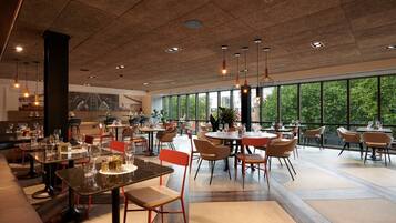 A spacious restaurant with high ceilings, large windows, and modern furnishings.