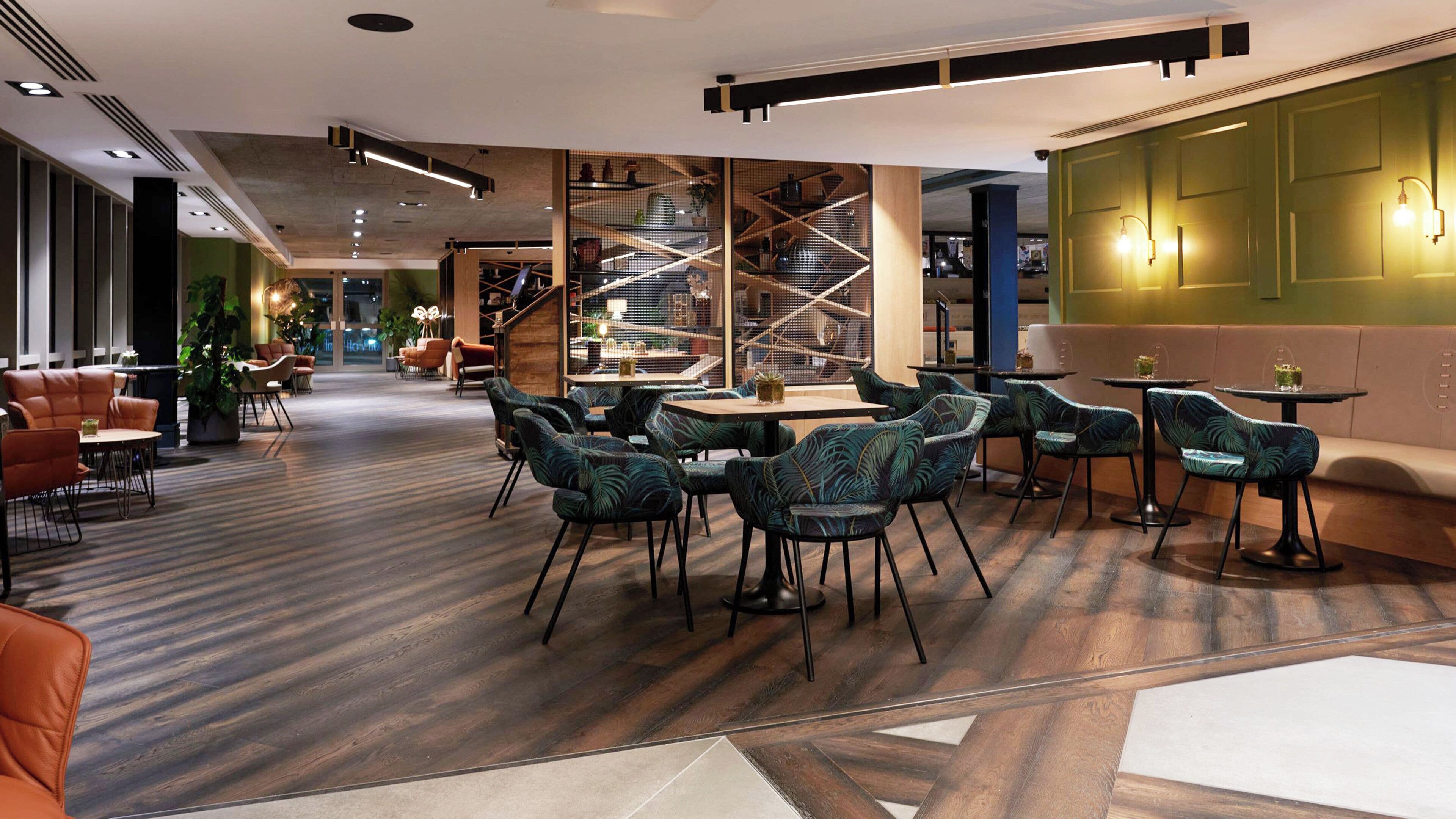 A modern interior with a mix of seating areas, including sofas and chairs, and a staircase with a geometric design.