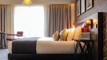 Una habitación de hotel con una cama, una mesita de noche con una radio, una silla y un escritorio.