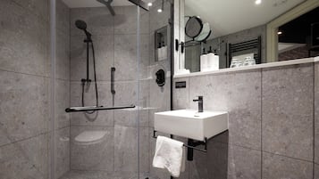 A modern bathroom with a glass-enclosed shower, a white sink, and a large mirror.